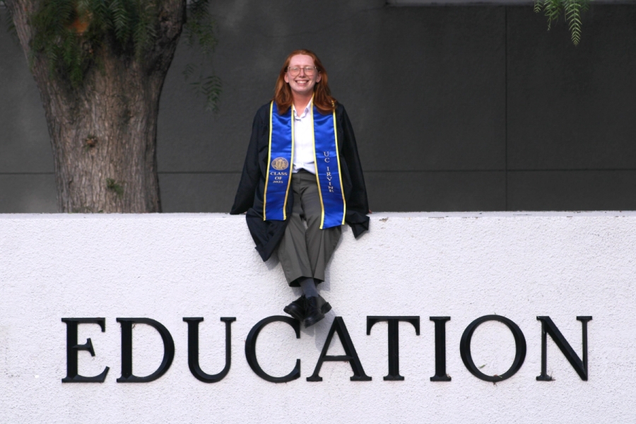 Girl sitting on school sign.
