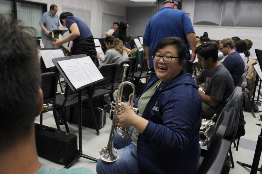 Girl holding trumpet and laughing.