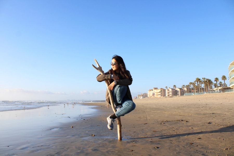 Girl sitting on stick looking at the ocean.