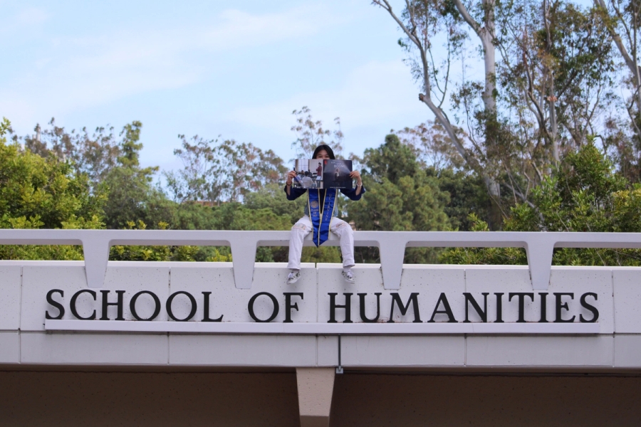 Girl sitting on school sign with poster.