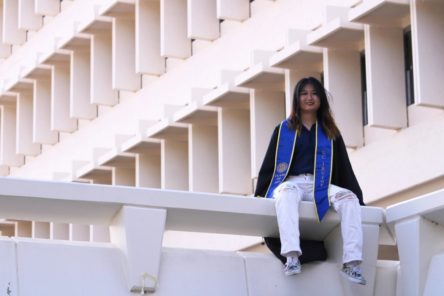 Girl sitting in front of white building.