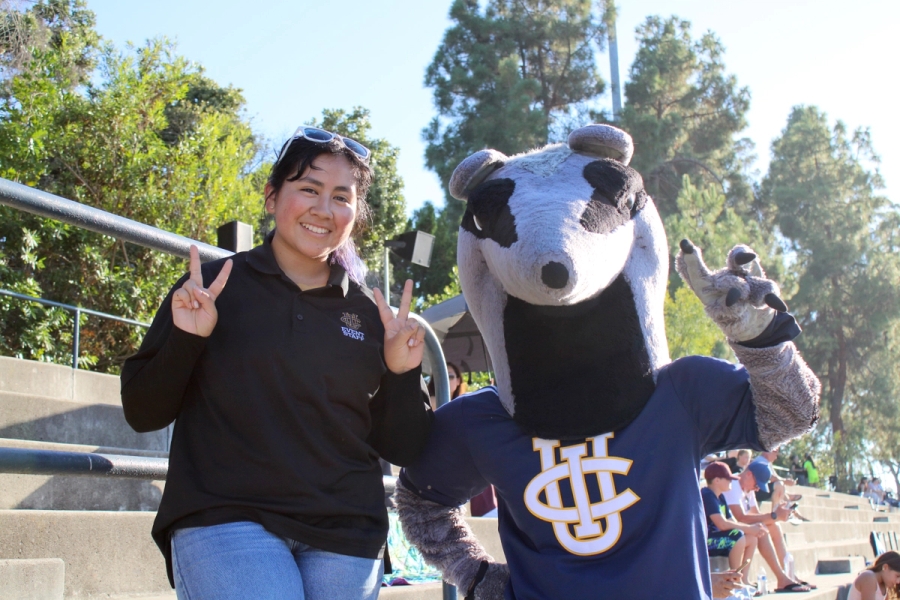 Girl holding up peace sign with Peter the Anteater.