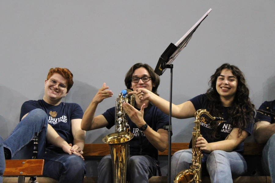 Boy and girl pointing at baritone sax while other boy smiles.