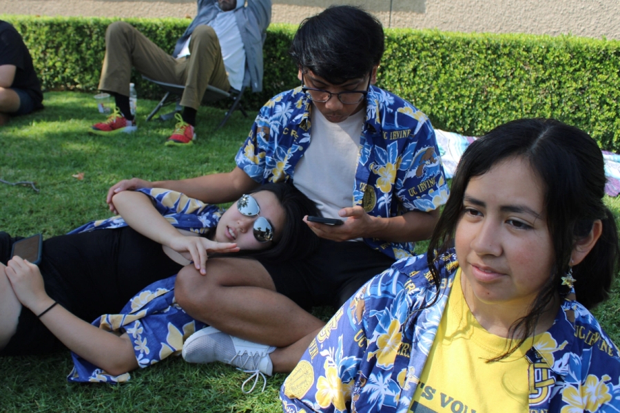 Two girls and a boy sitting on the grass.