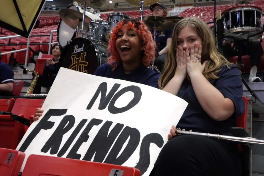 Two girls holding 'No Friends' sign.