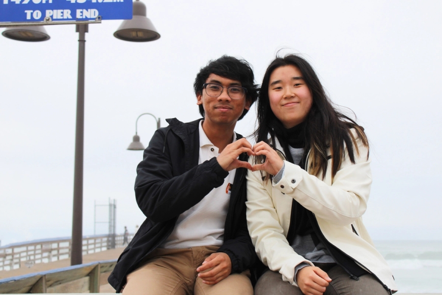 Boy and girl making a heart with hands.