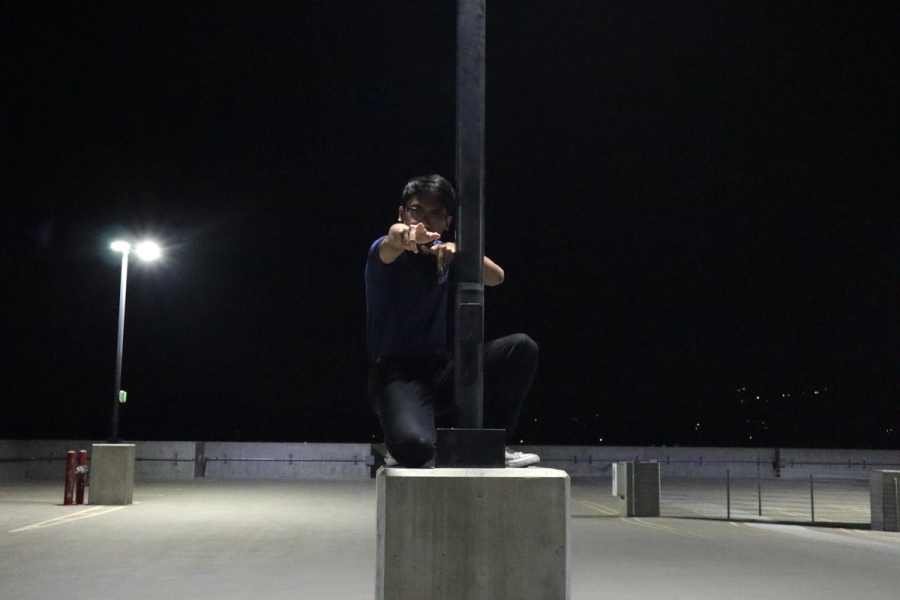 Boy pointing to camera on lamppost.