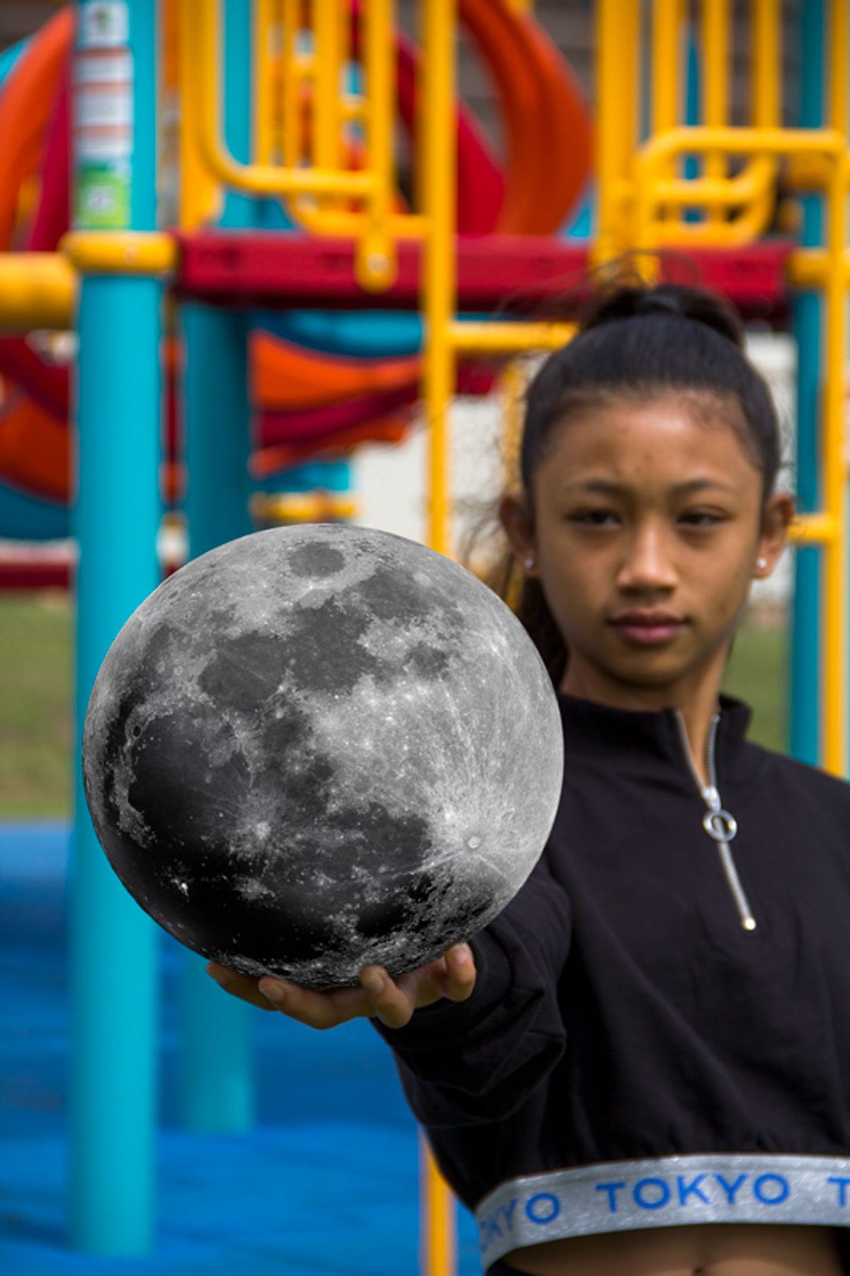 Girl holding the moon in the palm of her hand.