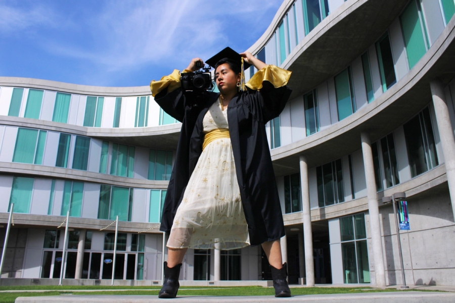 Girl in grad fit taking picture of camera.