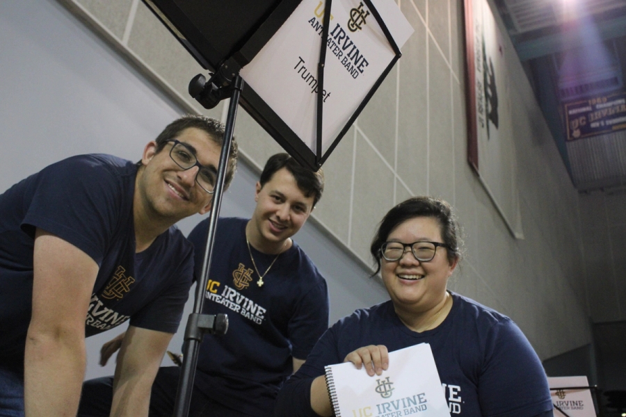 Three alumni holding a band book.
