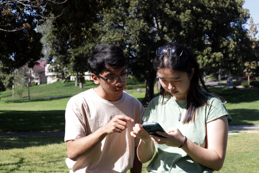 Boy pointing at girl's phone.