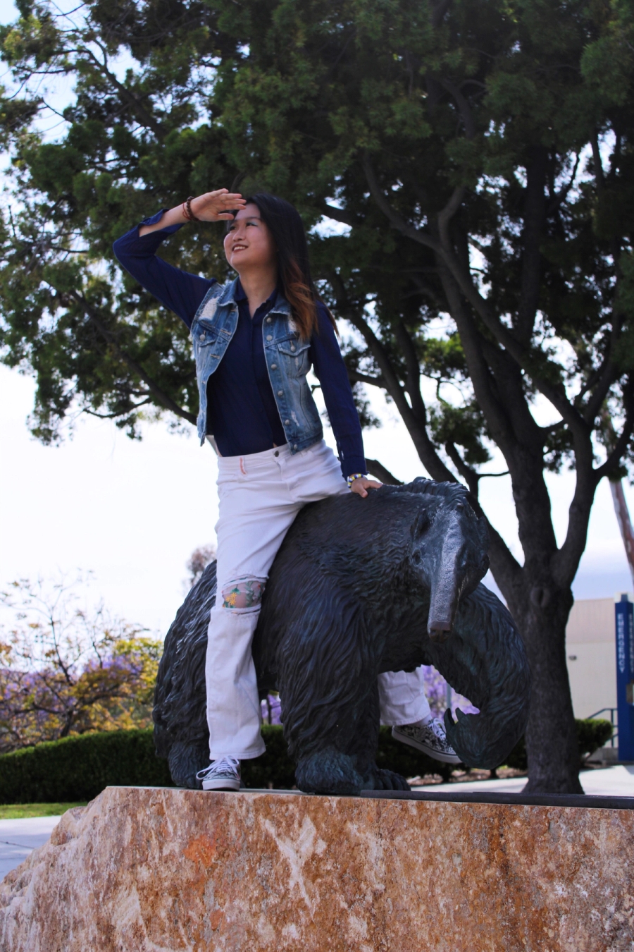 Girl sitting on anteater statue searching.