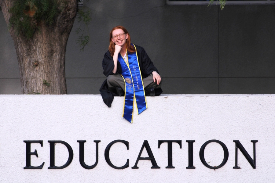 Girl sitting crossed legged on school sign.