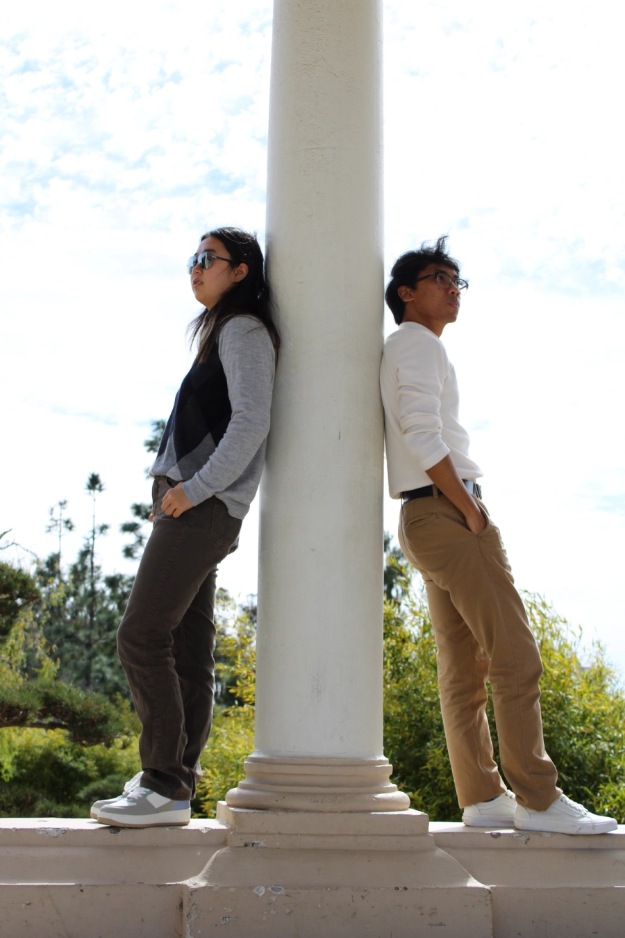 Girl and boy leaning against pillar.