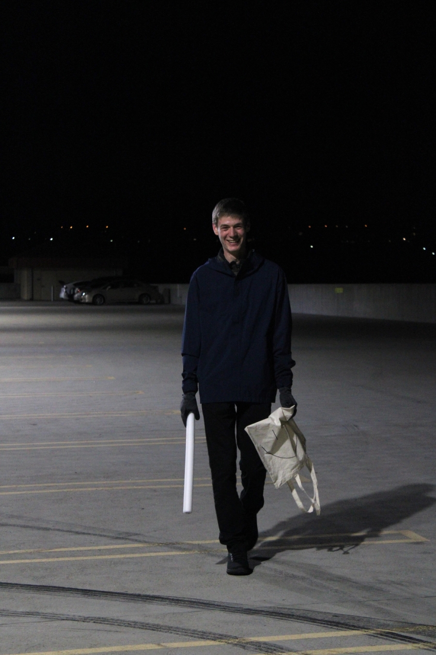 Boy holding a light saber and a tote bag.