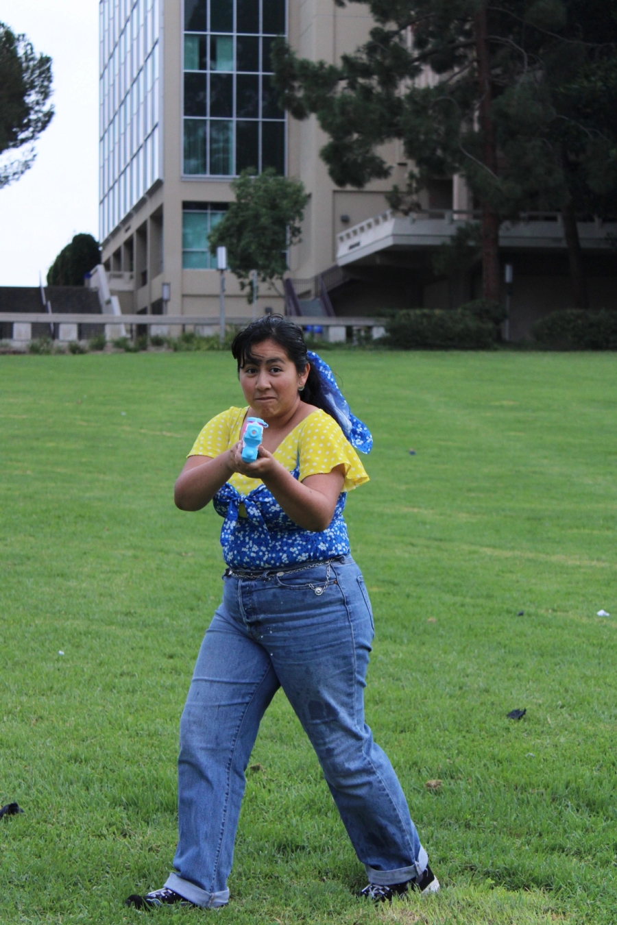 Mexican girl pointing water gun at camera.
