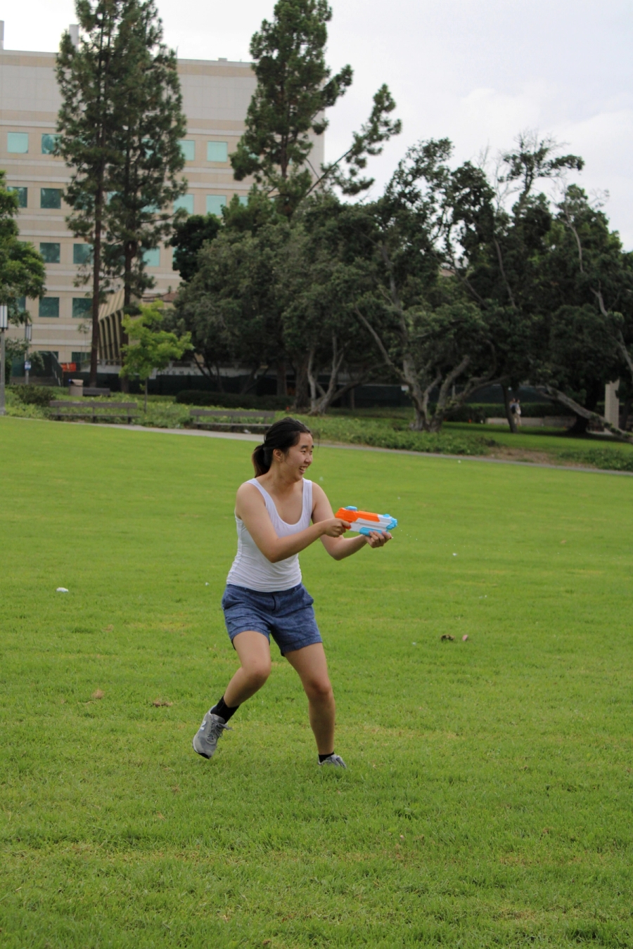 Asian girl shooting water gun to the right.