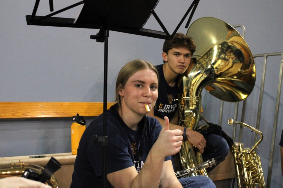 Girl holding a thumbs up with reed in mouth.