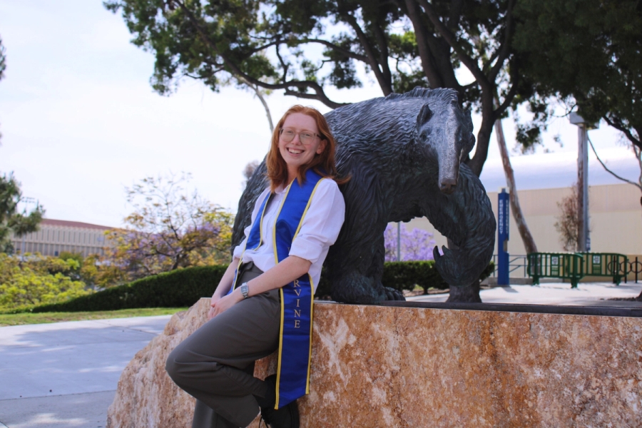 Girl leaning on anteater statue with leg up.