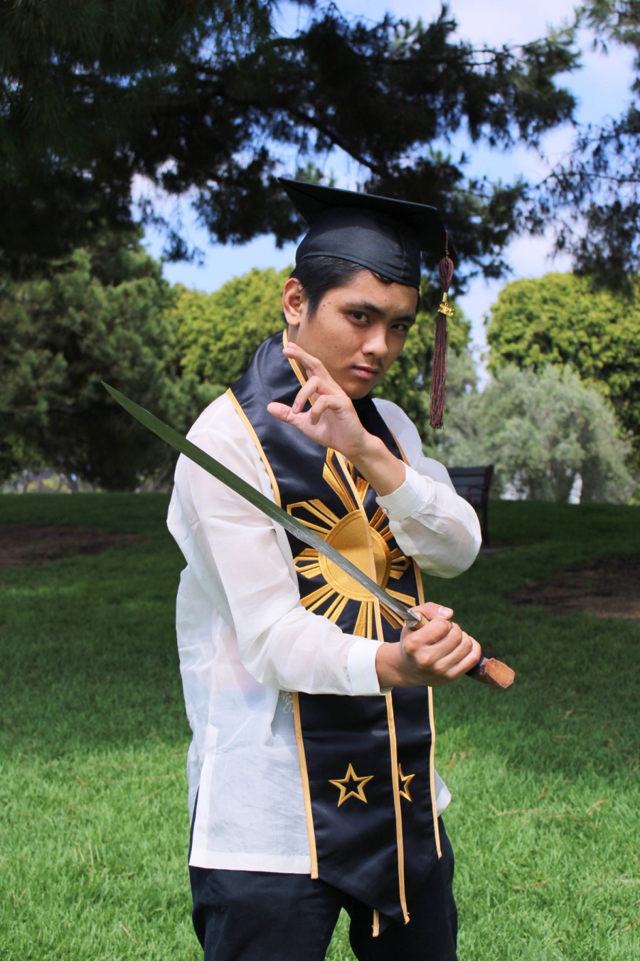 Man in Filipino stole and cap with large sword.