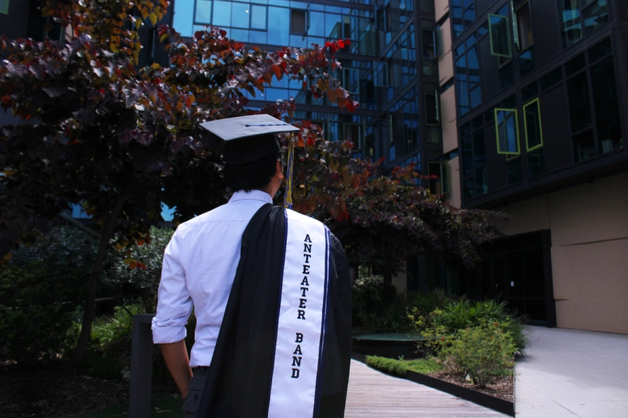Behind boy walking with grad fit over shoulder.