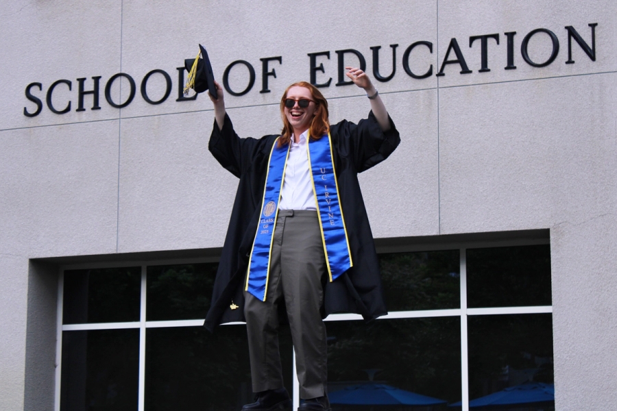 Girl posing in front of school sign with grad fit.