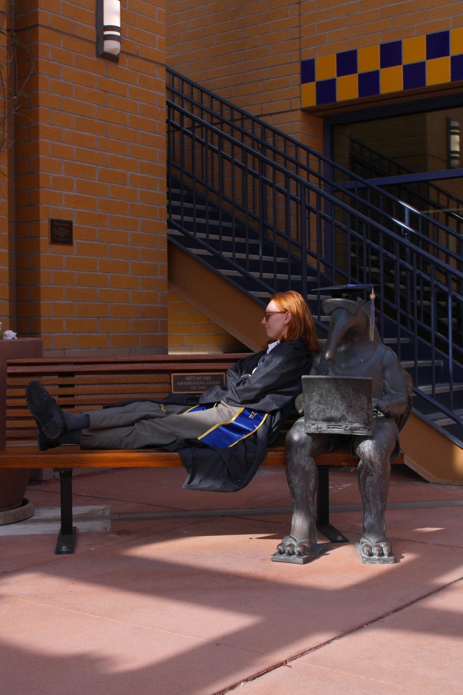 Girl sitting near grad anteater statue.