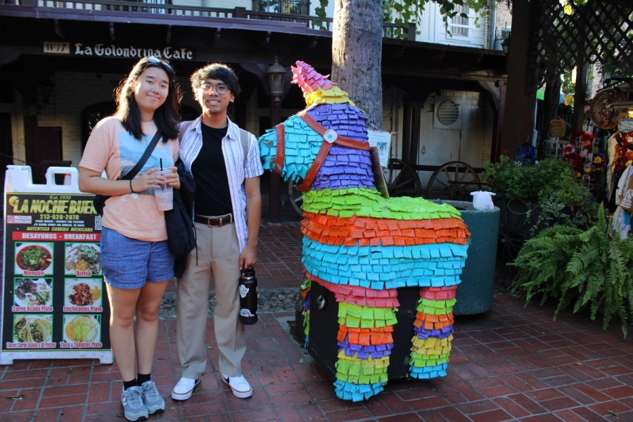 Boy and girl posing next to pinata.