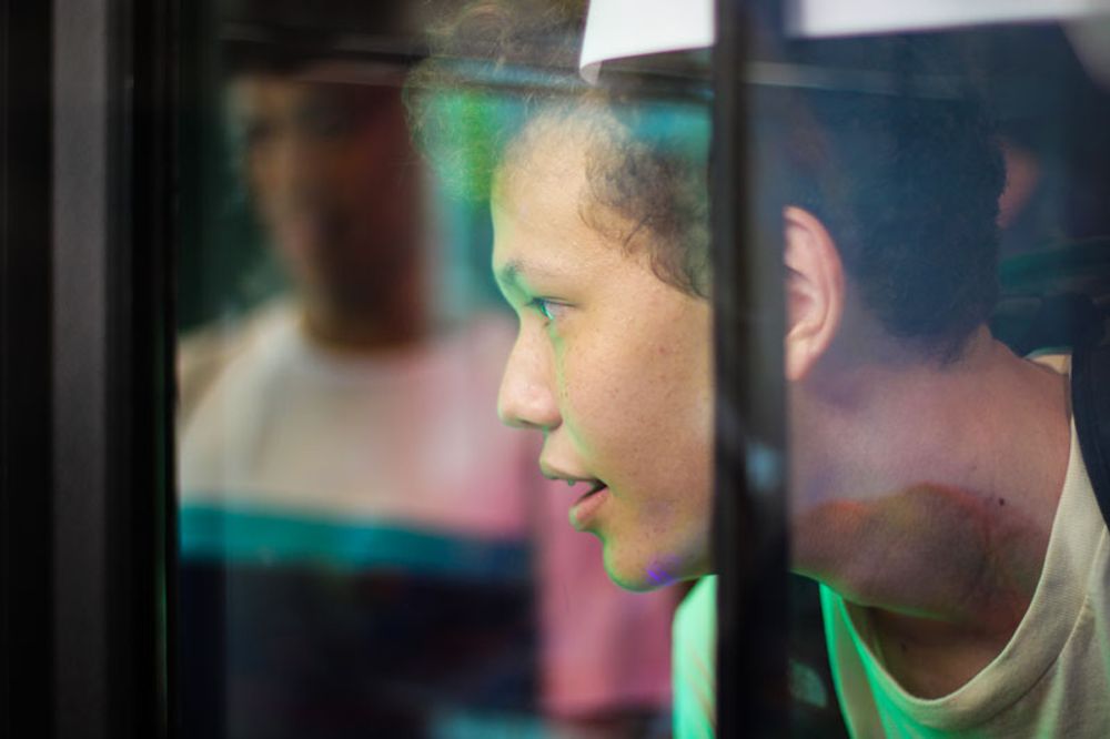 A boy staring at the inside of a claw machine.