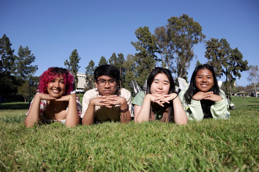Three girls and a boy posing on grass.