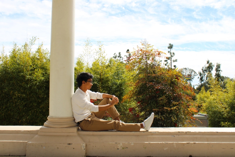 Boy sitting against pillar.