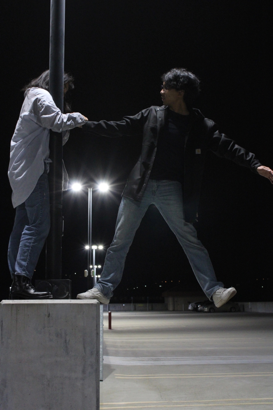 Girl holding guy who has one leg off lamppost.