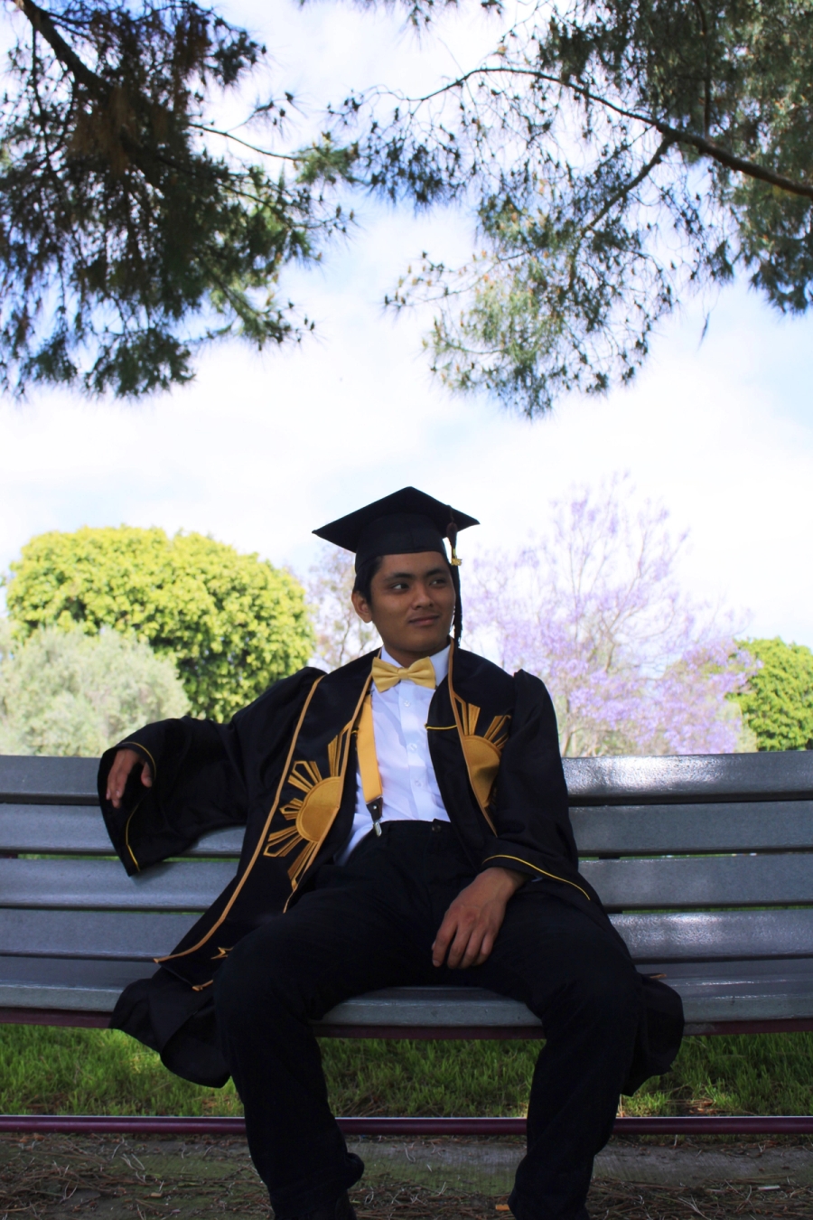 Man in grad fit sitting on bench.