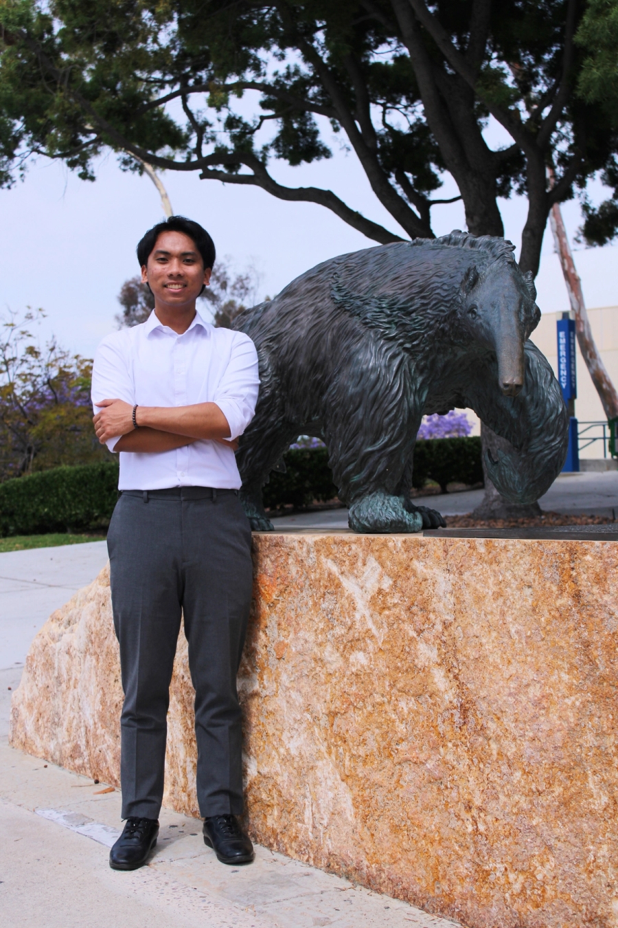 Boy standing near anteater statue.