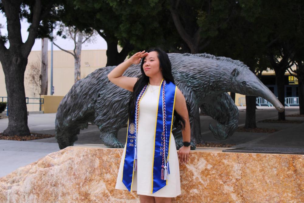 Girl saluting in front of anteater statue.