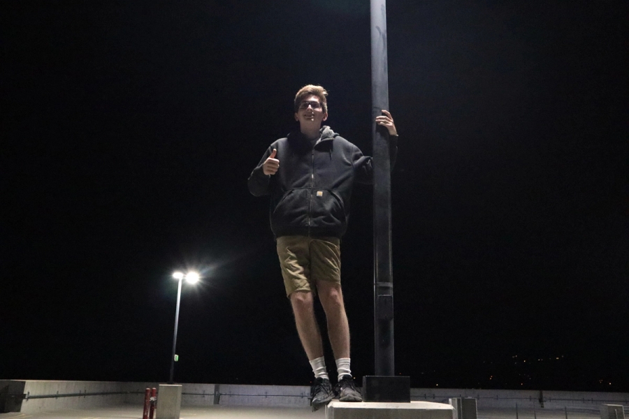 Boy with thumbs up on lamppost.