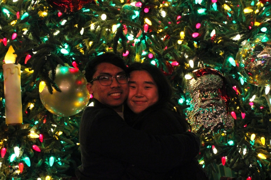 Boy and girl hugging in front of tree.