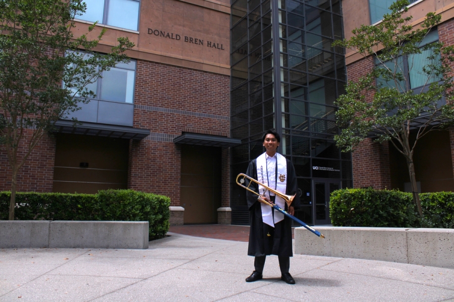 Boy holding trombone in grad fit.