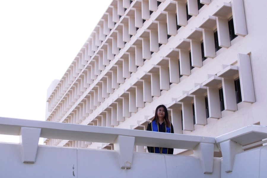 Girl standing in front of white building.