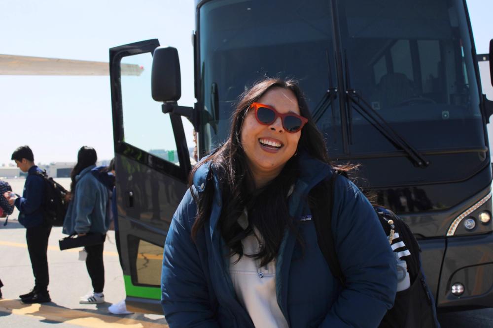 Woman smiling in front of charter bus.