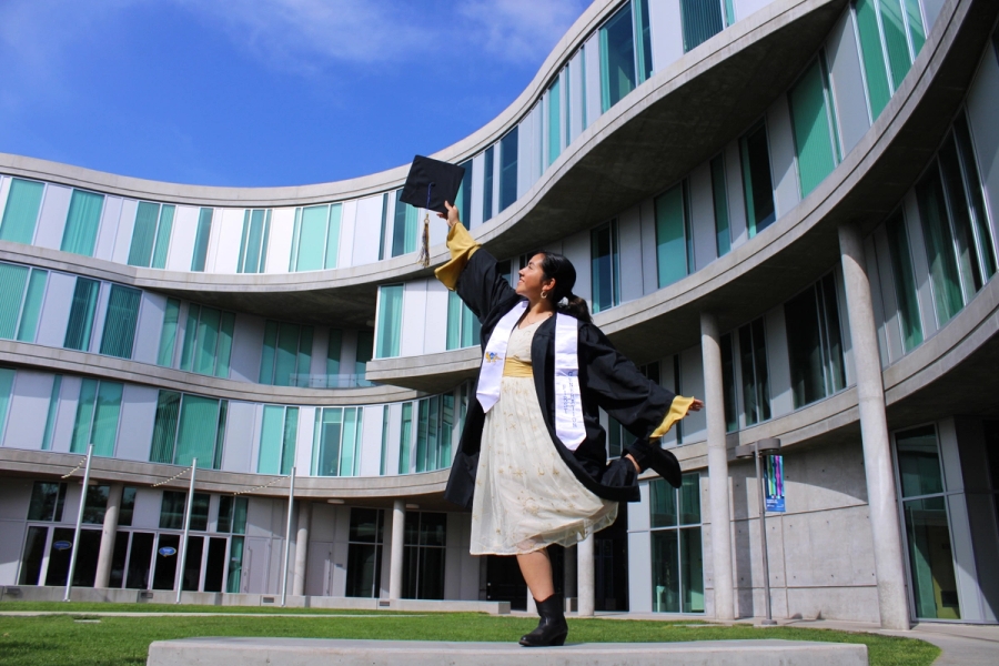 Girl in grad fit holding cap up.