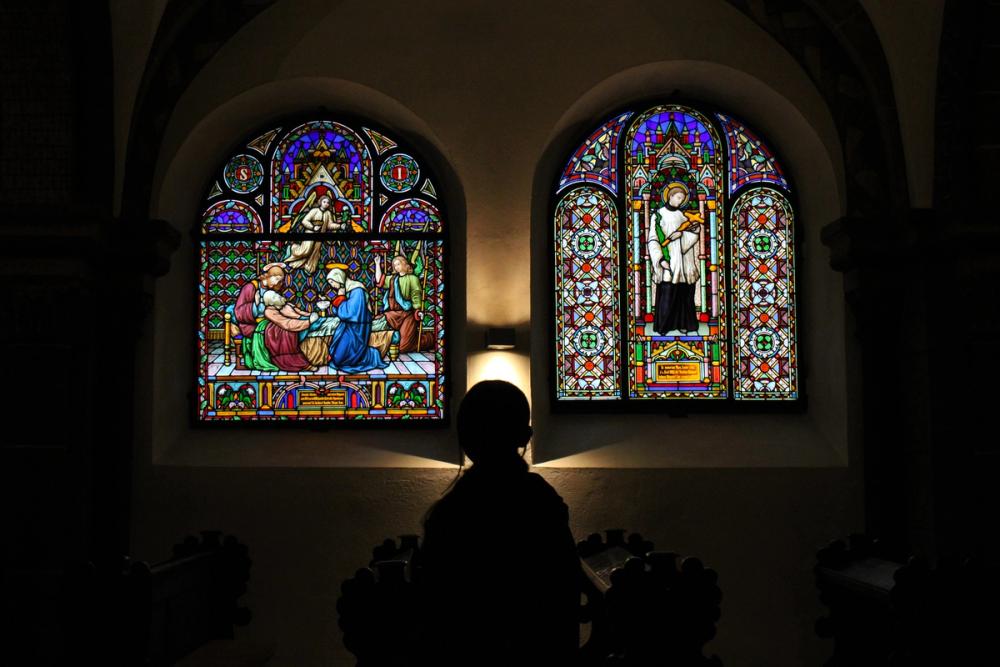 A girl staring at stained glass windows.