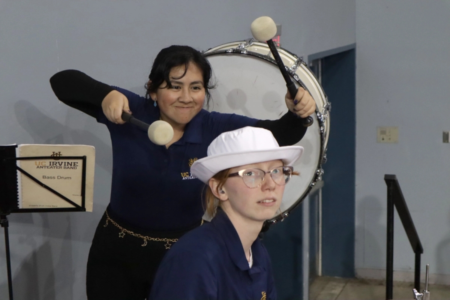 Girl pretending to drum on another girl's head.
