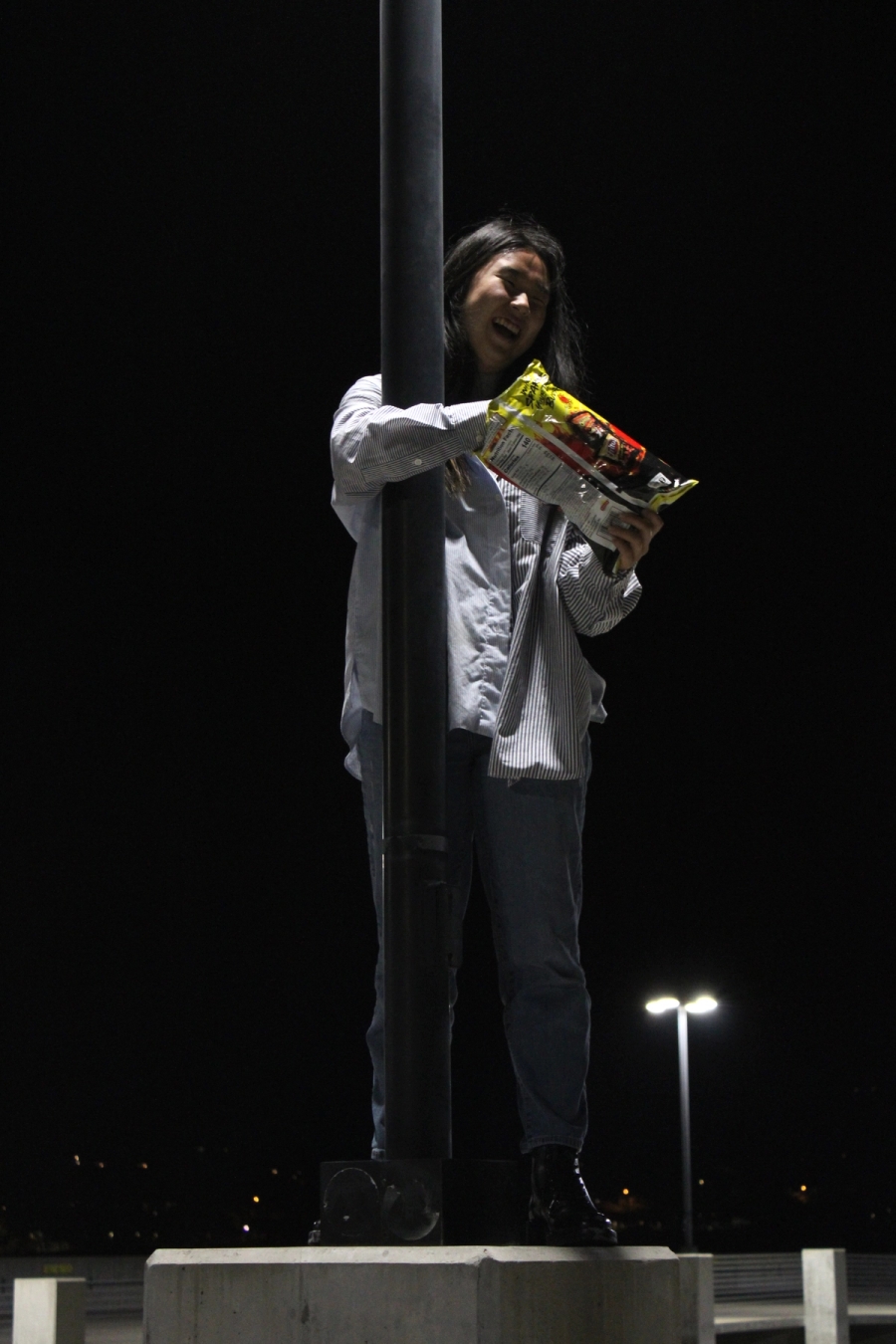 Girl eating chips on lamppost.