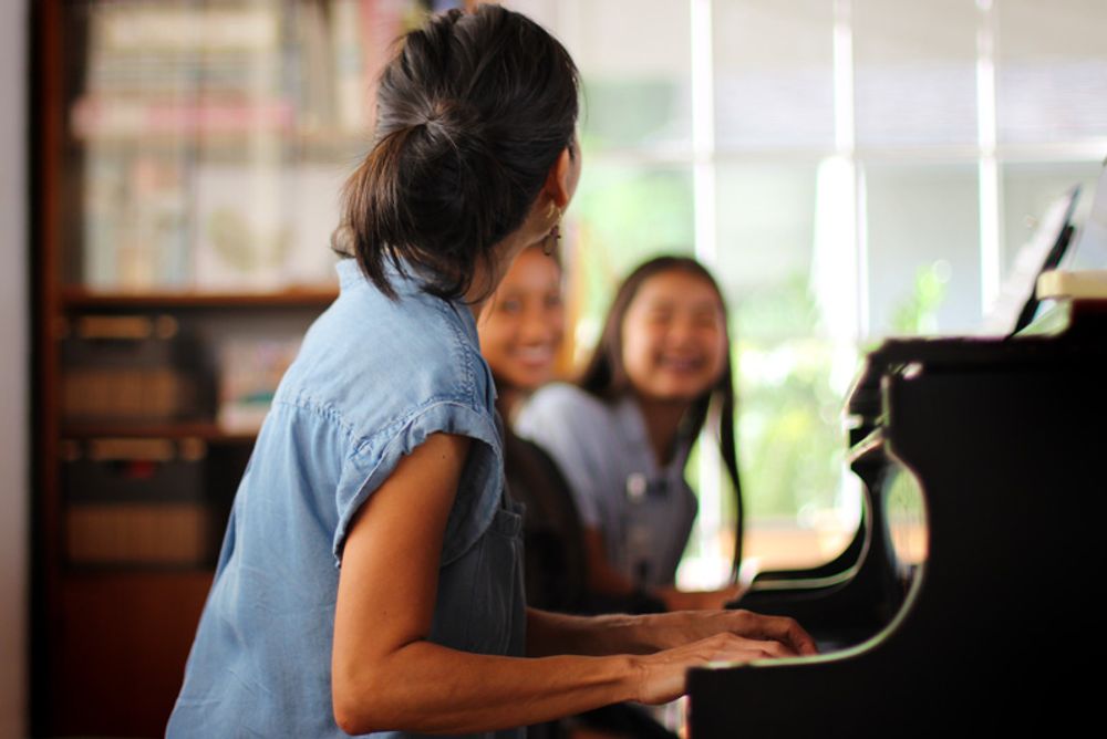 A piano teacher teaching two of her students.
