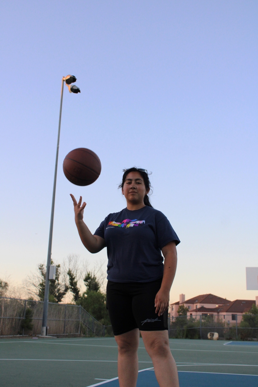 Girl throwing basketball up with one hand.
