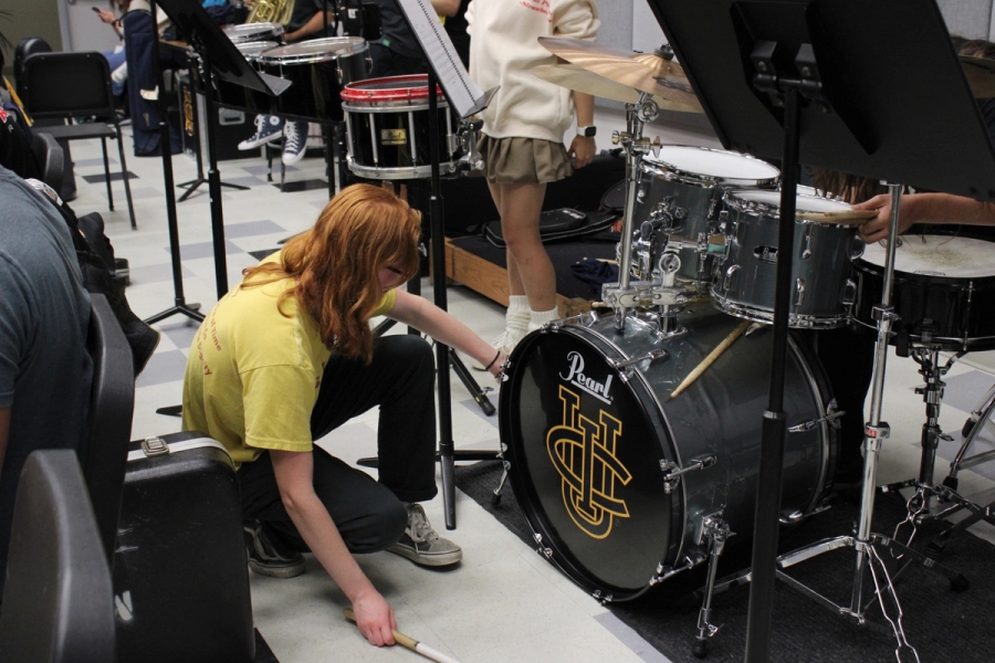 Girl fixing drum on drumkit.