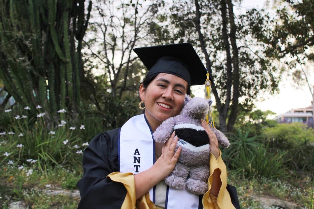 Girl in grad fit holding an anteater plush 1.