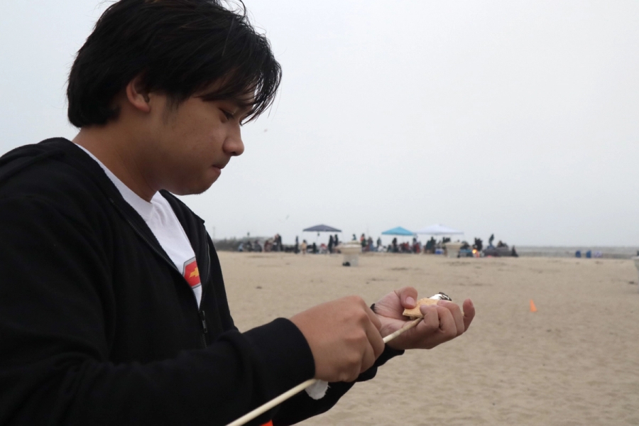 Boy putting a marshmallow on stick.