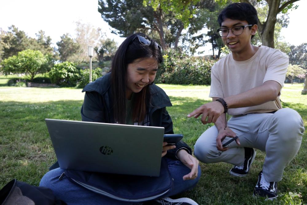Girl on laptop, boy pointing.